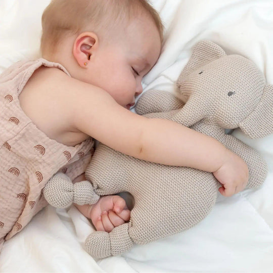 Baby hugging a crocheted elephant plush toy while sleeping