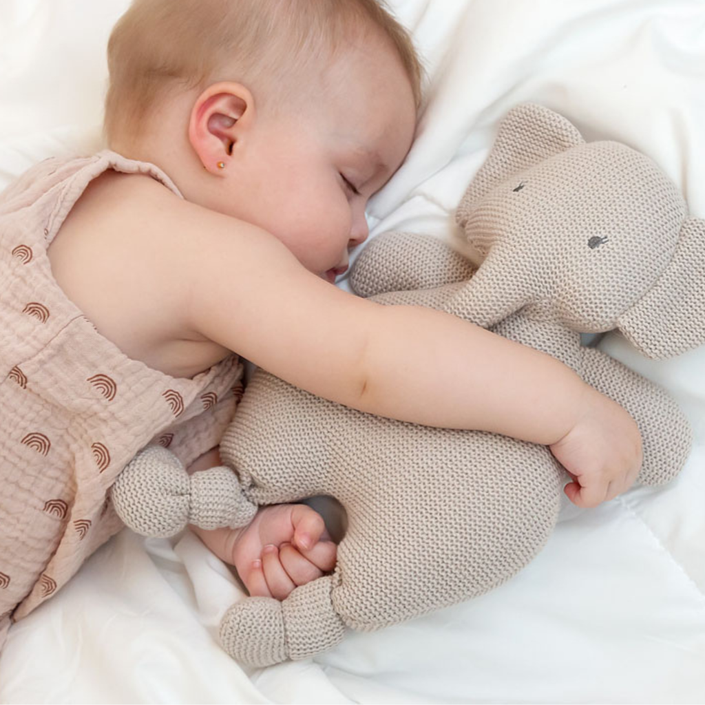 Bebé abrazando un peluche de elefante hecho a crochet mientras duerme