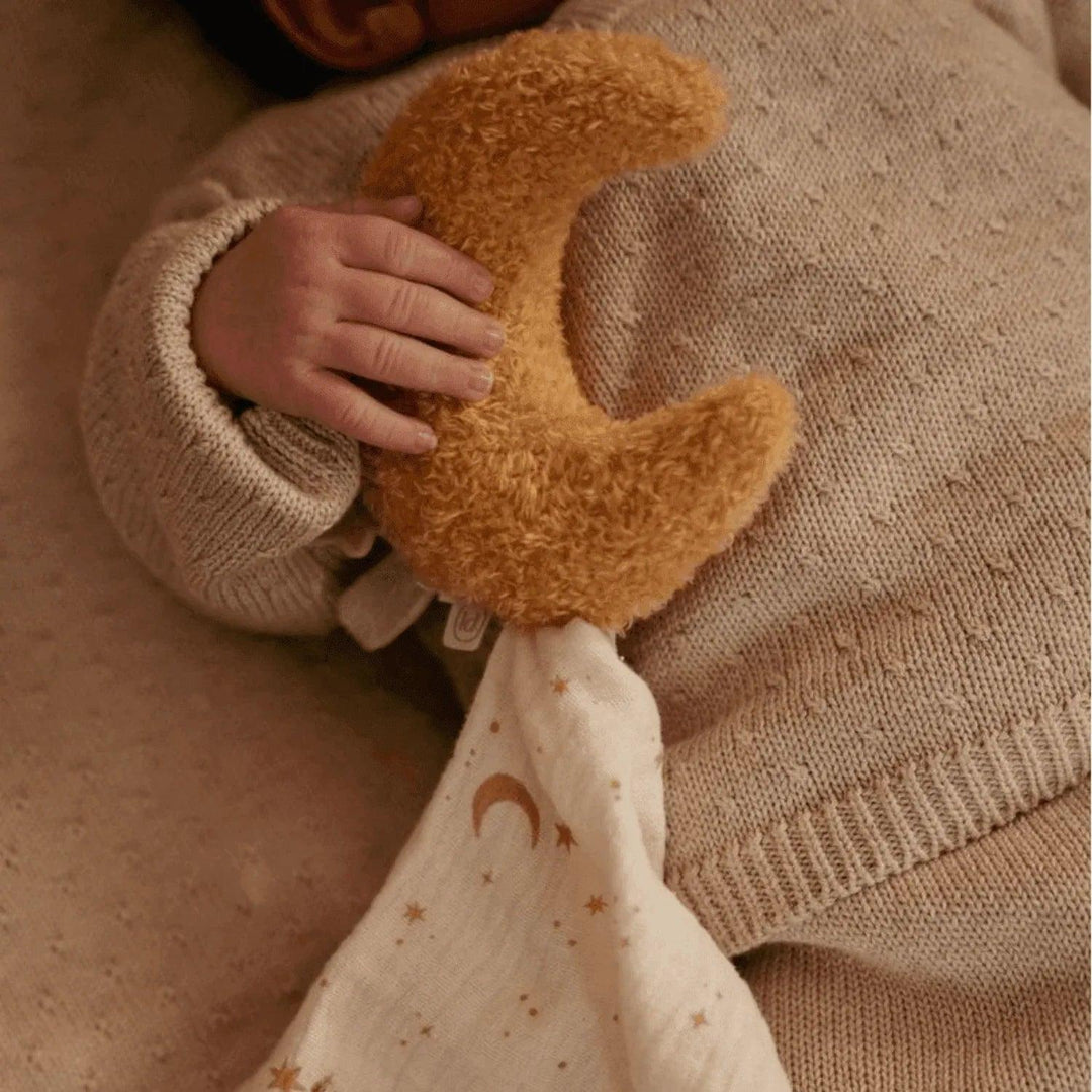 Bébé tenant une douce peluche lune Little Dutch dans les tons moutarde et beige