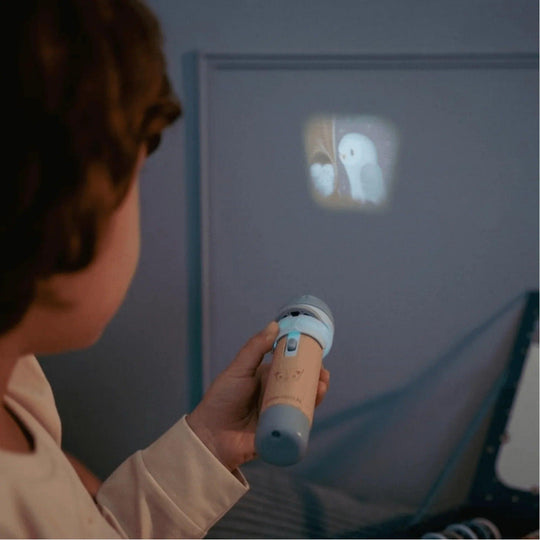 Un enfant utilise un projecteur de lampe de poche pour afficher l'image d'un livre d'histoires sur un mur