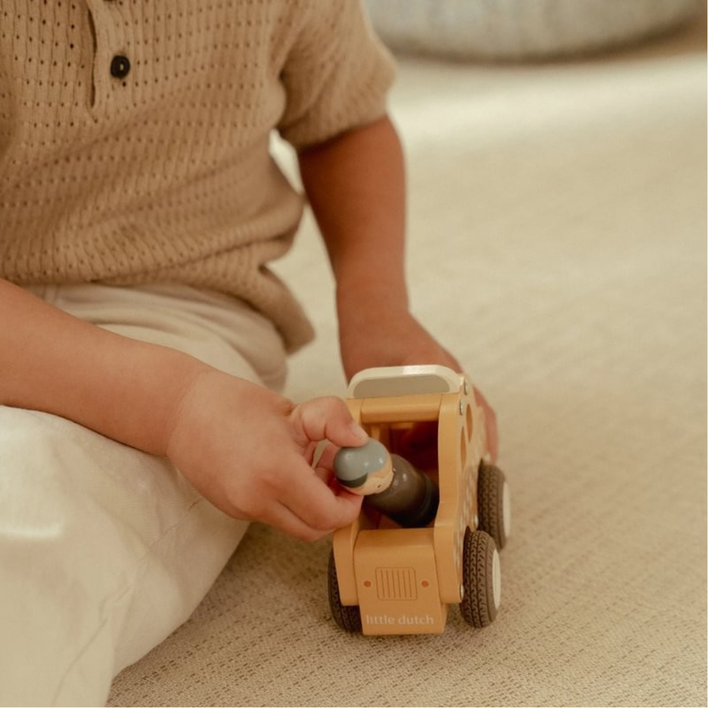 Niño jugando en el suelo con un taxi de madera Little Dutch, colocando la figura del conductor en el vehículo