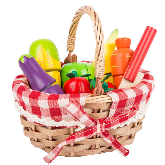Juguete cesta de la compra rellena de fresas, zanahoria, berenjena, mazorca de maíz, manzana y plátano. Cesta de mimbre forrada con tela a cuadros rojos y blancos.